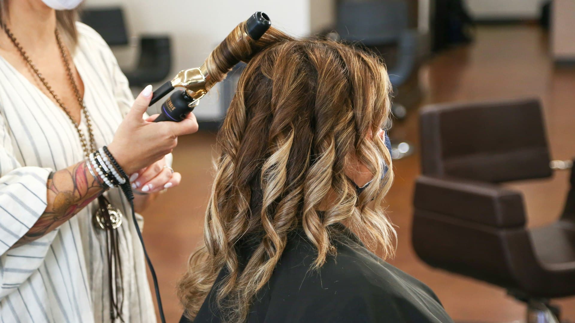 Estilista usando una plancha rizadora en el cabello de una clienta en un salón